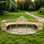 Beige travertine marble garden bench with curved design placed on a stone patio in a landscaped garden