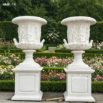 Pair of large carved marble plant pots with pedestal in garden