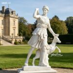 Side view of life-size white marble Diana of Versailles goddess statue with deer