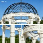Detailed view of ornate white marble column and carved architrave of a luxury garden gazebo with black wrought iron dome