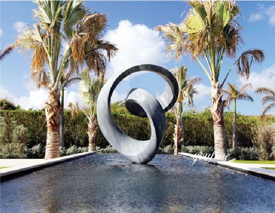 Abstract ring-shaped grey marble sculpture reflecting in water feature