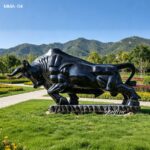 Polished black marble bull sculpture installed in a scenic outdoor plaza