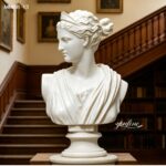 Marble bust of Diana the Huntress displayed in a classic library with bookshelves and stairs
