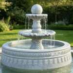 Front view of a sesame gray granite rolling ball fountain with carved basin and double wave tiers.