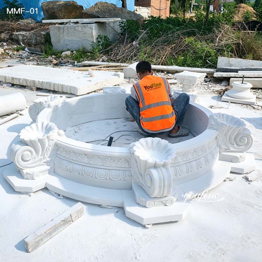 Craftsman hand carving a natural marble fountain during production process