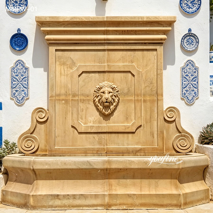 Artisan-carved beige marble wall water fountain set against a wall with blue ceramic tiles