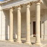 Light beige marble pillars for sale, smooth tapered columns providing support and elegance to a classical-style building