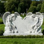 Kneeling angels marble heart headstone in a peaceful cemetery setting
