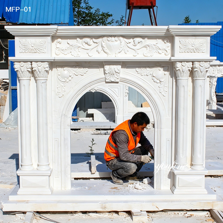 Worker finishing a white carved marble fireplace surround at the factory