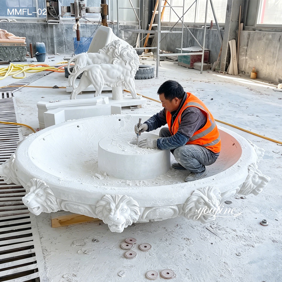 Craftsman working on a hand-carved marble lion fountain basin during production.