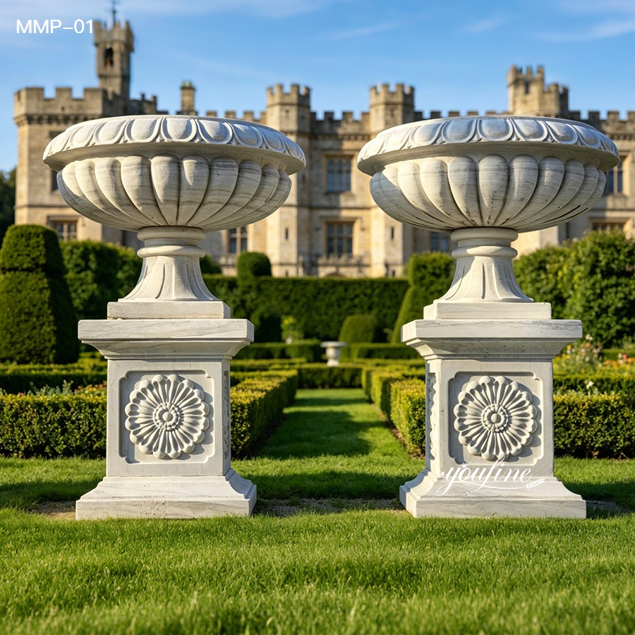 Elegant marble garden urn with ribbed bowl and intricately carved square pedestal, outdoor landscaping.