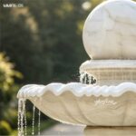 Close-up of the rolling marble ball fountain showing the polished marble sphere, scalloped basin edge, and flowing water details.
