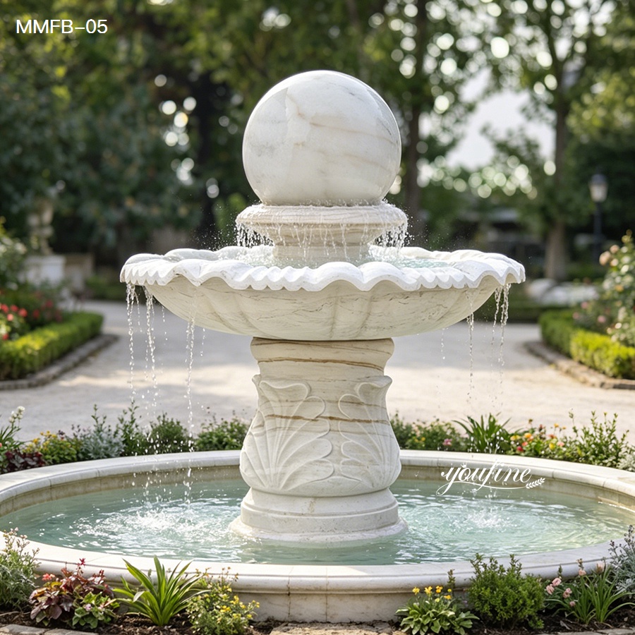 White rolling marble ball fountain placed in an elegant courtyard, featuring hand-carved pedestal relief and smooth water flow.