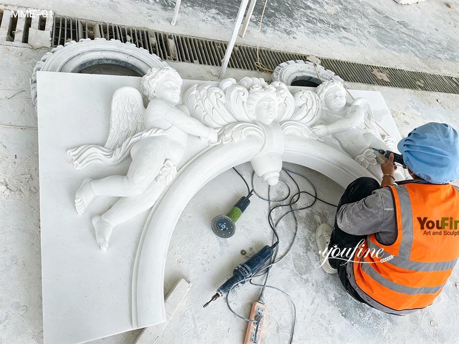 Artisan carving details of a custom white marble door frame with angel reliefs