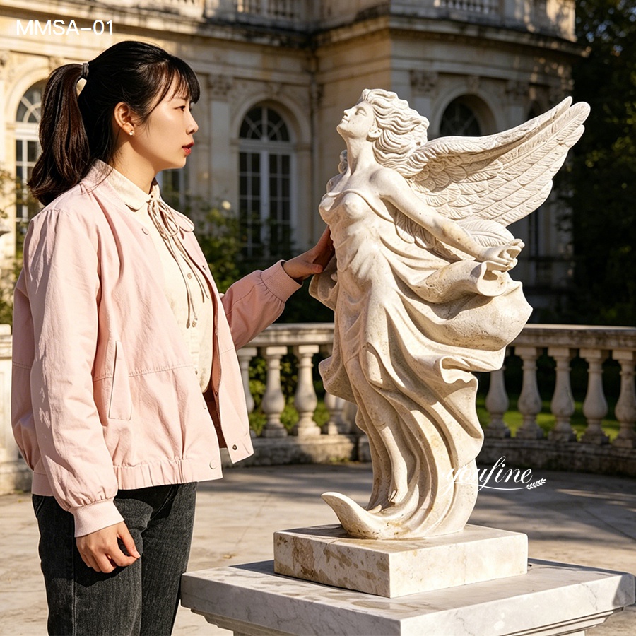 Close-up view of a woman touching the wing of a natural marble angel statue in a classic garden setting