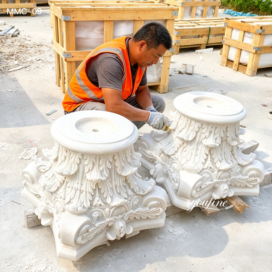 A skilled artisan wearing an orange safety vest is intricately carving ornate marble capitals outdoors, surrounded by wooden crates.