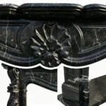 Close-up of intricate carvings on polished black marble featuring floral and curved patterns, highlighting fine craftsmanship.