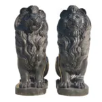 A pair of intricately detailed black marble lion sculptures with flowing manes, seated on rectangular bases.