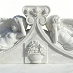 A finely carved marble sculpture featuring two reclining angels with detailed wings and floral basket relief accents.