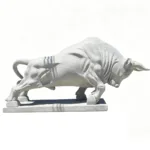A detailed marble sculpture of a charging bull, depicting strength and motion, placed on a smooth pedestal against a white background.