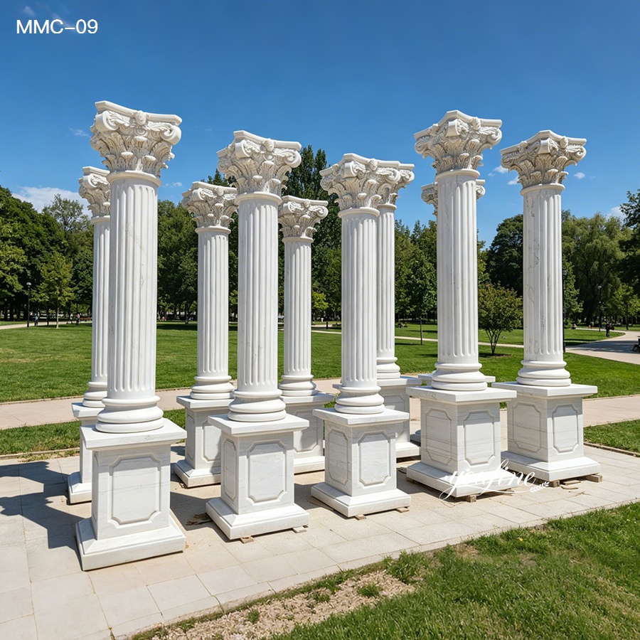 Eight white marble Corinthian pillars displayed outdoors on a sunny day, showcasing intricate carvings and classical architectural design.