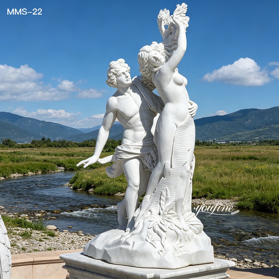 Elegant white marble sculpture depicting two human figures beautifully carved, placed outdoors alongside a serene river and mountains.