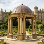 Circular marble gazebo with intricately carved columns and copper dome surrounded by lush European garden landscaping.