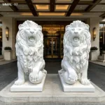 Two intricately carved white marble lion statues in a roaring posture, displayed symmetrically at a luxurious entrance with warm lighting.