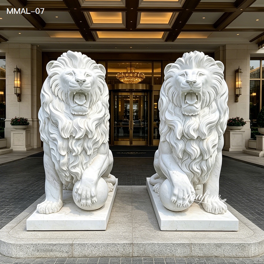 Two intricately carved white marble lion statues in a roaring posture, displayed symmetrically at a luxurious entrance with warm lighting.