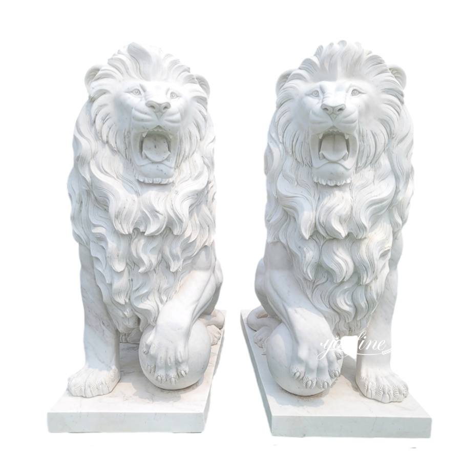 A pair of intricately carved white marble lion statues with detailed manes and fierce expressions, positioned on solid bases.