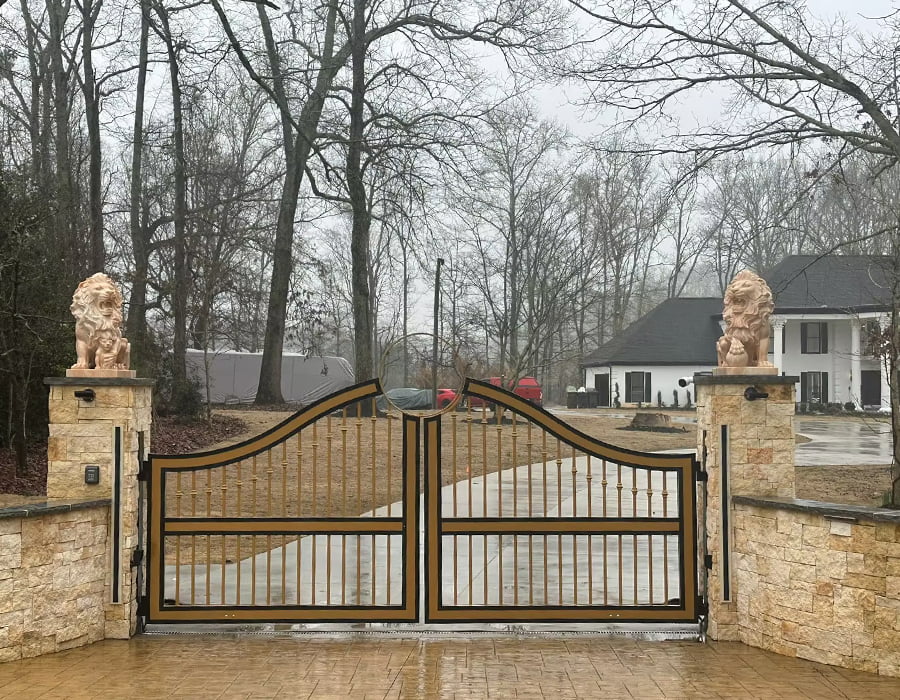 Ornate driveway gate with lion statues and stone pillars
