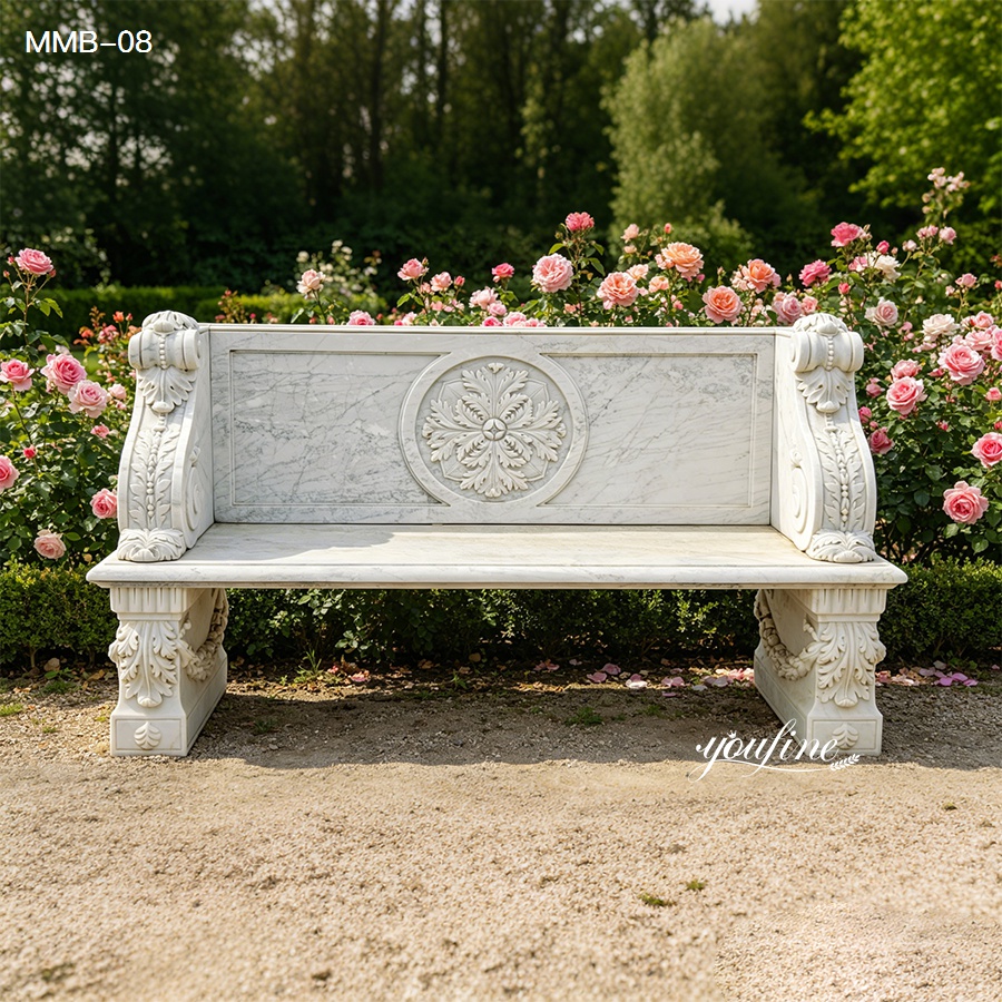 Intricately carved marble bench with floral designs surrounded by blooming pink roses in a lush garden.