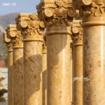 Close-up view of intricately carved marble columns in warm yellow tones, showcasing classical designs and polished surface.