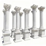 A set of intricately carved white marble Corinthian columns with ornate capitals and strong square bases, arranged in an open area.