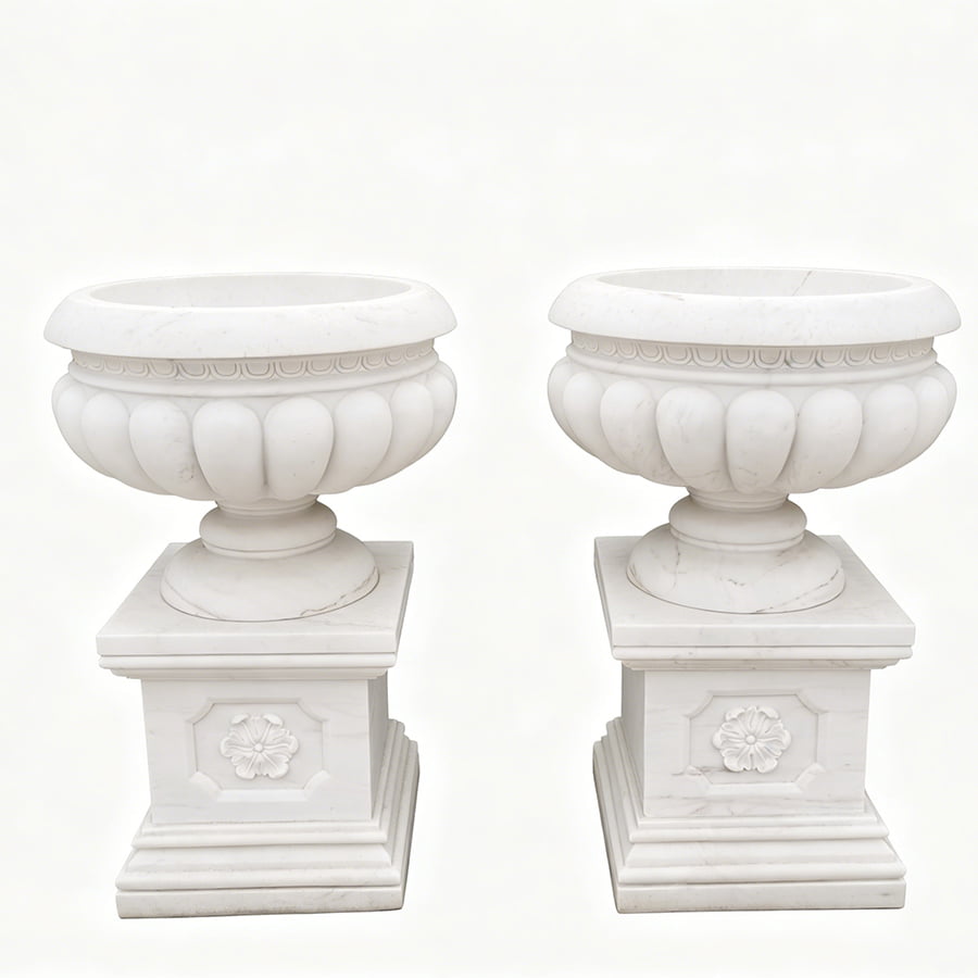 A pair of white marble garden planters with intricate carvings and decorative pedestals, showcasing refined craftsmanship.