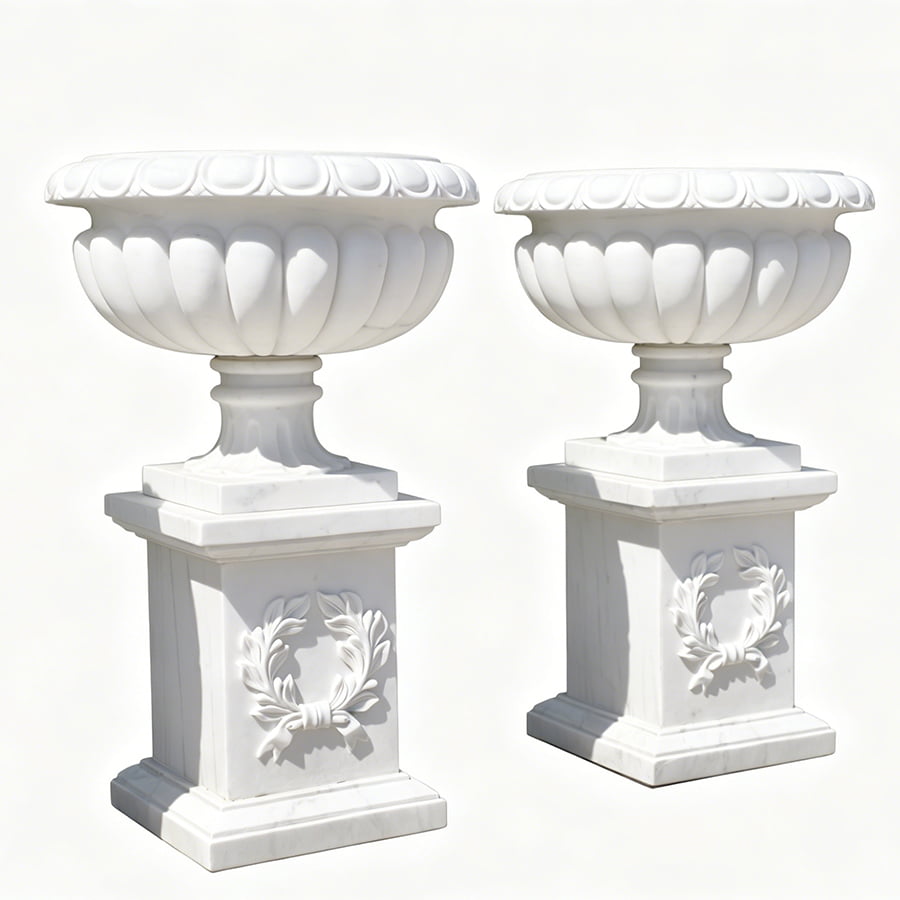 Two elegant white marble urns mounted on pedestal bases with intricate decorative carvings, showcasing classic luxury design.