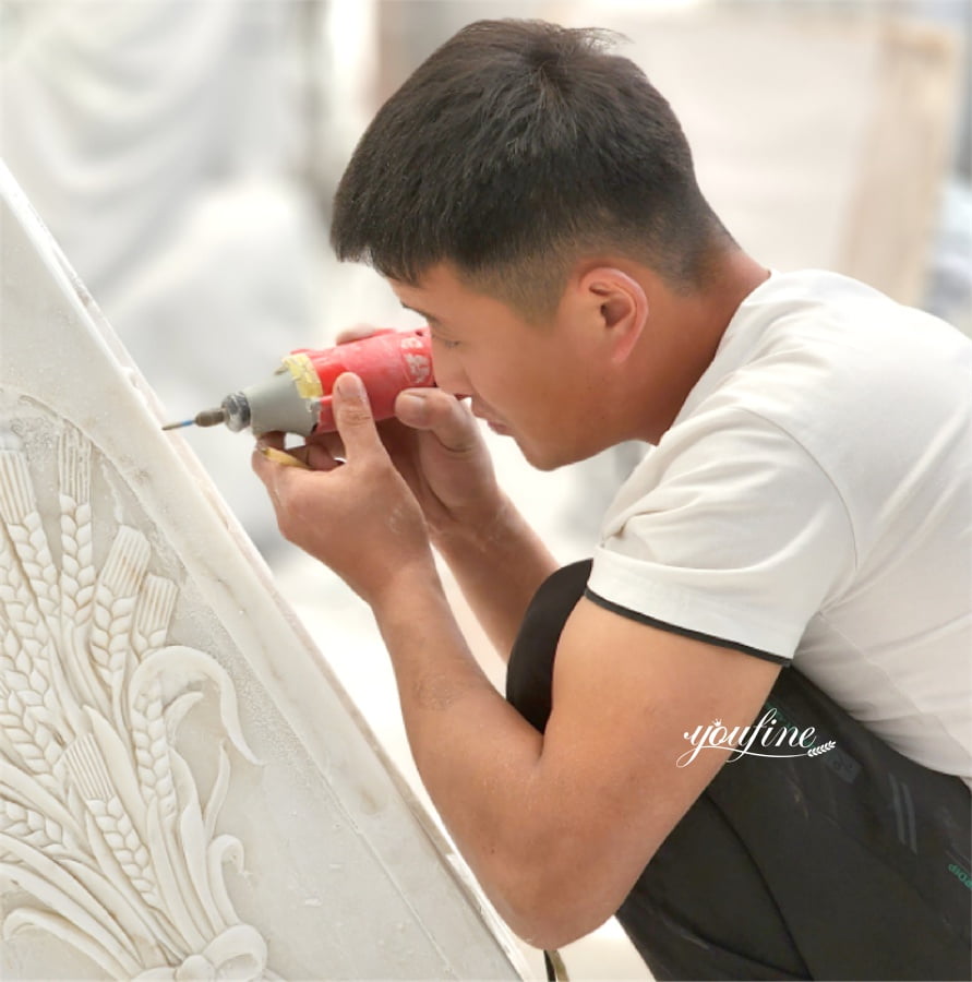 A skilled artisan carefully engraves an intricate wheat design into marble.
