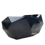 A sleek black marble bathtub with a geometric design featuring sharp angles and smooth polished surfaces, ideal for modern luxury interiors.