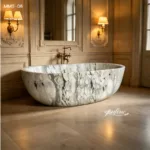 Luxury marble bathtub with intricate natural patterns in an elegant bathroom featuring classic wall sconces and ornate decor.