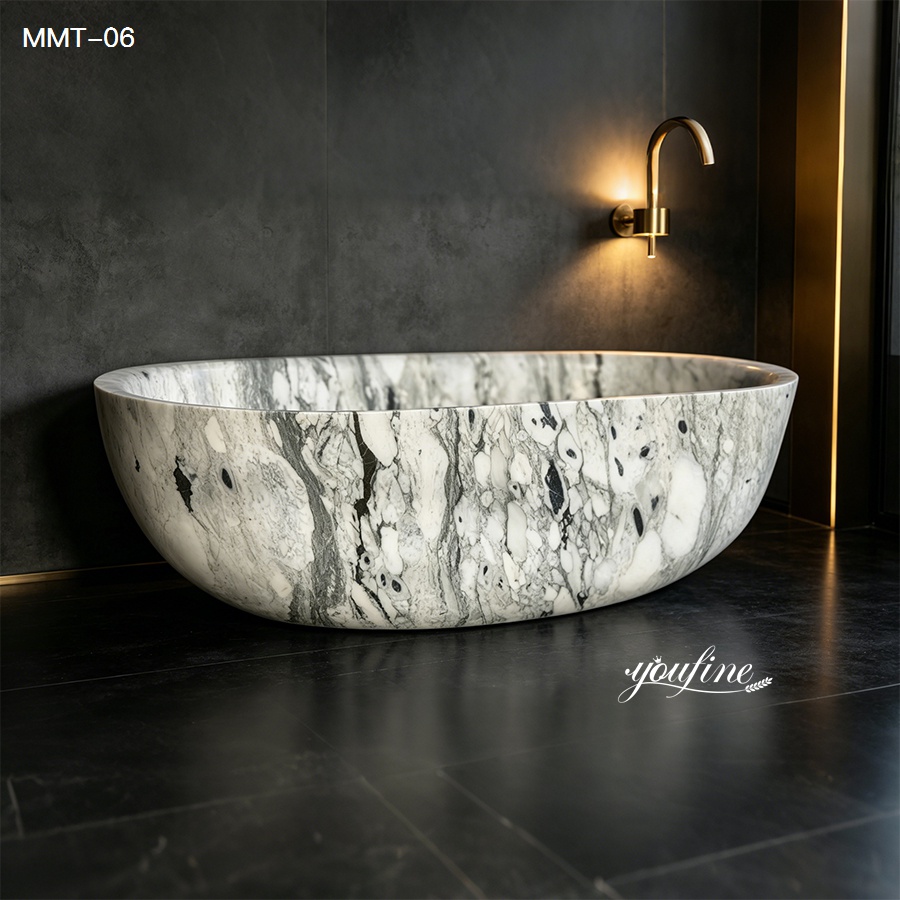 Luxurious marble bathtub with unique veining in a modern bathroom featuring dark stone walls and gold accents.