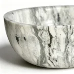 A close-up of an elegant marble bowl with intricate gray and white veining, showcasing smooth craftsmanship and luxurious design.