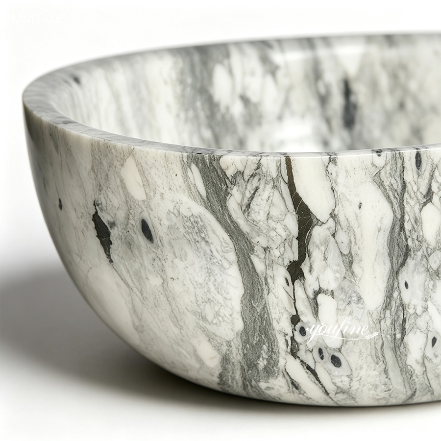A close-up of an elegant marble bowl with intricate gray and white veining, showcasing smooth craftsmanship and luxurious design.