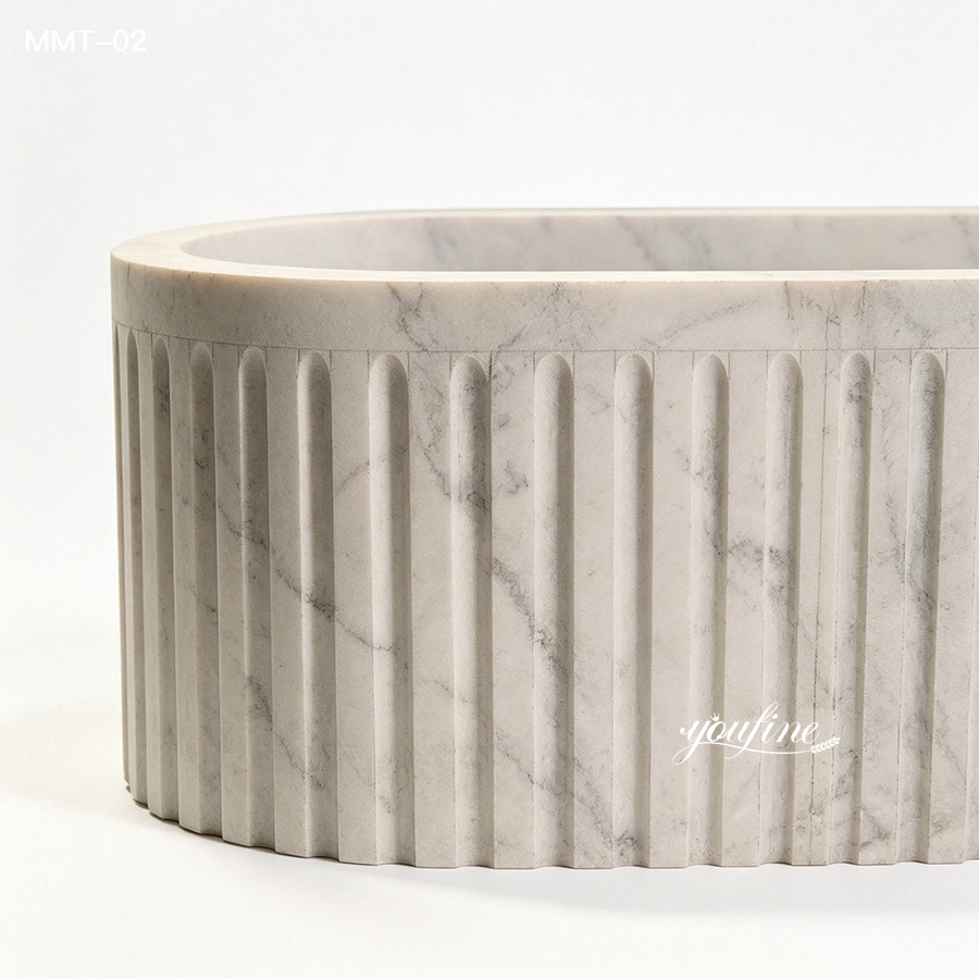 An oval marble sink with a fluted pattern and smooth design, showcasing refined craftsmanship and luxurious material.