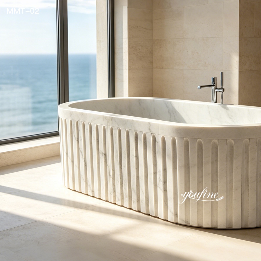 Luxurious modern marble bathtub with sleek fluted design placed near a window overlooking the ocean in a bright bathroom.