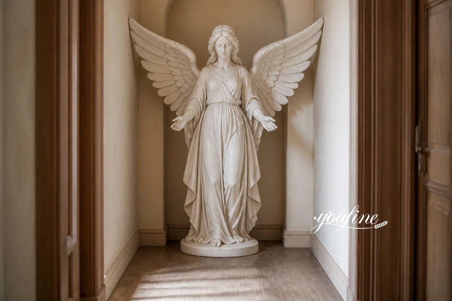 A carved white marble angel sculpture with open wings placed in a narrow hallway with soft lighting and wooden accents.