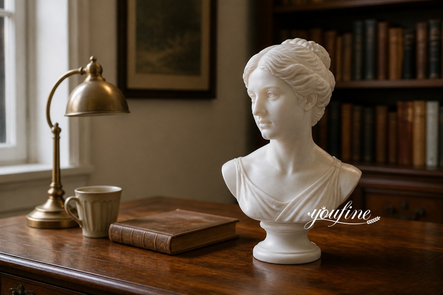 A white marble bust of a woman placed on a wooden study desk with a brass lamp, a coffee cup, and a book in a classic library setting.