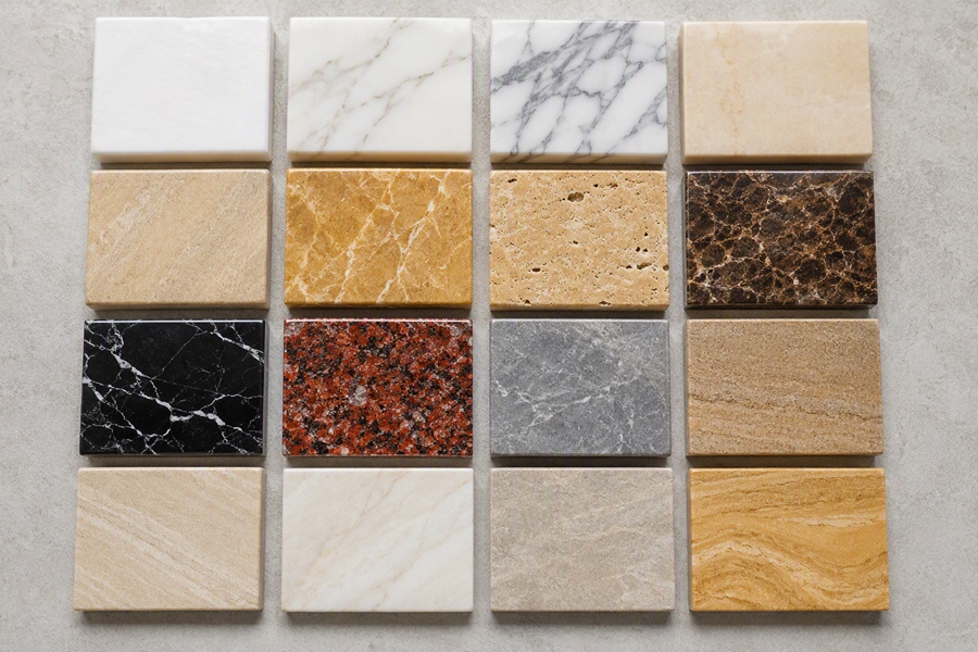 Assorted marble slab samples in various colors and textures neatly arranged on a neutral background for design selection.