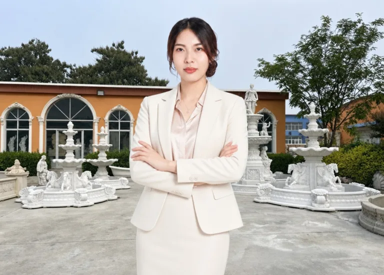 A confident businesswoman in a white suit standing with crossed arms in front of a garden featuring marble sculptures and fountains.