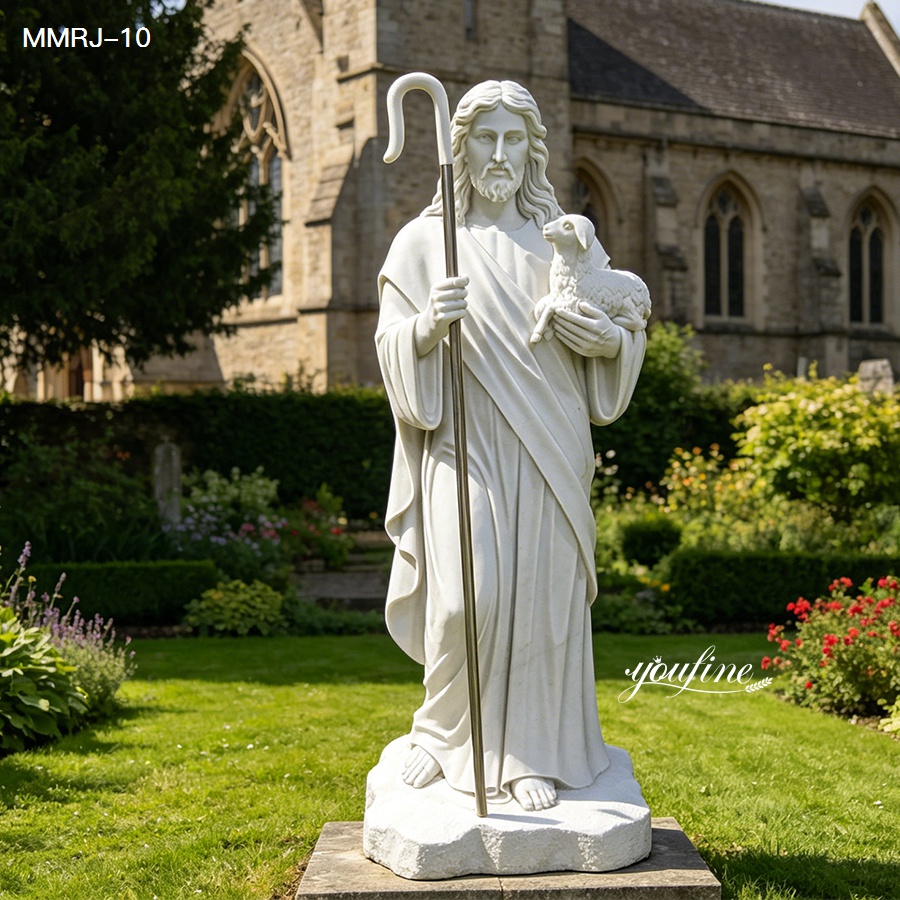 Marble statue of the Good Shepherd holding a lamb, set in a landscaped garden with a church in the background.