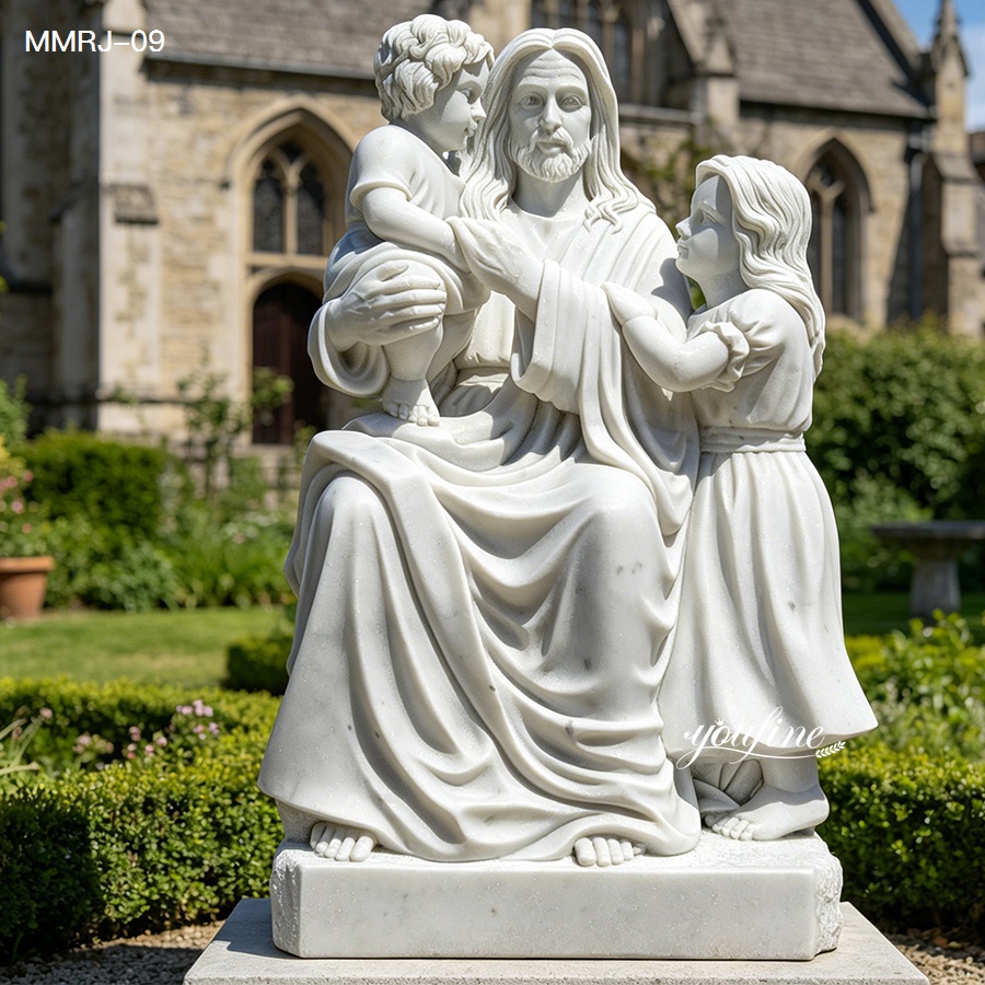 Intricately carved white marble statue of Jesus seated with children, placed in a garden setting near a church building.